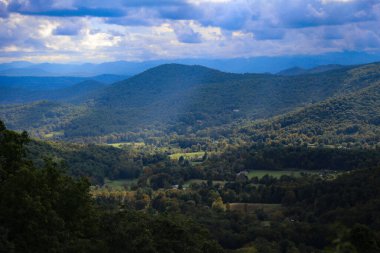 Dağlık bir bölgedeki renkli, yoğun ormanlardan oluşan güzel bir manzara.