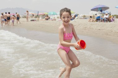Pembe bikinili kız güneşli bir yaz gününde kumsalda mutlu mesut oynuyor, Vera, İspanya