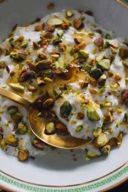 Yunan anahtar kasesinde yeşil şam fıstıklı yoğurt ve altın kaşıklı bal