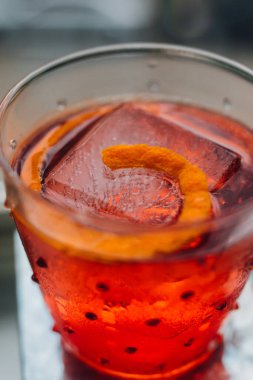 elektrikli kırmızı turuncu Negroni kokteyli pencere pervazında yemyeşil arka planda