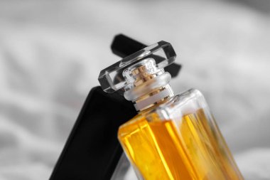 Bulanık arka planda beyaz bir çarşaf üzerinde iki parfüm şişesinin yakın plan çekimi.