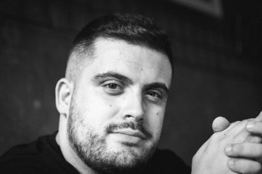 Beyaz tenli, yakışıklı beyaz bir erkeğin yüzünü gösteren gri tonlu bir fotoğraf.