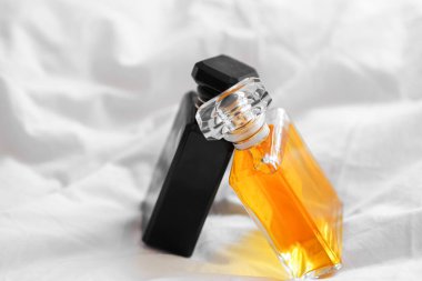 İki lüks parfüm şişesi bulanık arka planda beyaz bir çarşaf üzerinde