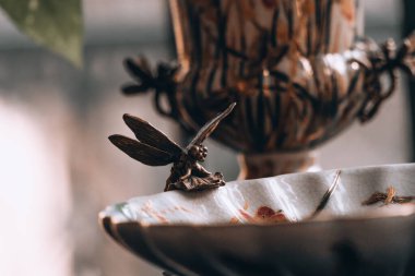 Bronz bir yusufçuk heykeli bulanık arka planda izole bir vaziyette duruyor.