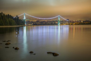 A beautiful view of Lions gate bridge over a river at night clipart