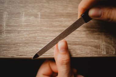 Tırnaklarını tırnak törpüsüyle törpüleyen bir kadının yakın plan fotoğrafı.