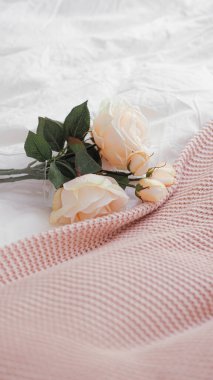 Dikey pembe bahçe gülleri ve beyaz buruşuk çarşaf üzerinde bir masa örtüsü.