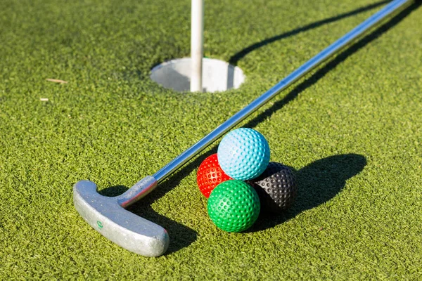 高尔夫球杆旁边靠近球门的四个彩色高尔夫球的特写镜头 — 图库照片
