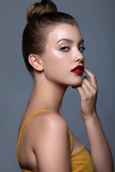 A portrait of a Caucasian female with hair in a bun and red lips