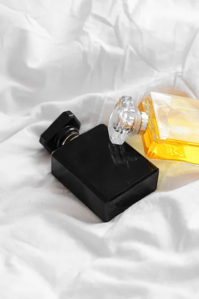 白いベッドシートの上に2本の香水瓶の垂直ショット — ストック写真