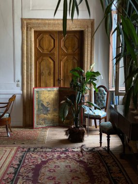 Eski bir İtalyan evinin dikey görüntüsü. Eski halılar, sandalyeler ve büyük ahşap bir kapı.