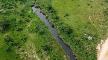 Yeşil otlağın yanında akan bir oturağın 4K havacılık çekimi