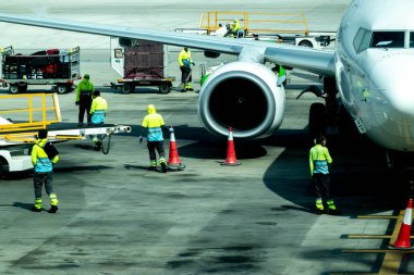 Hamad Uluslararası Havalimanı 'nda Dubai uçağının yanında duran erkek işçiler.