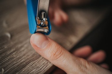 Tırnaklarını tırnak makasıyla kesen bir adamın yakın plan fotoğrafı..