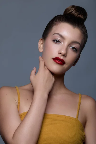 A portrait of a Caucasian female with hair in a bun and red lips