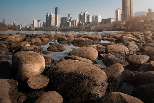 Closeup Shot Big Stones Surface Water Background City Skyscrapers — Stock Photo, Image