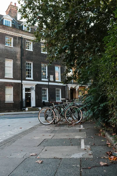 A vertical shot of a bike rack with bicycles near a residential black building in London, UK