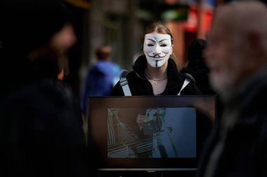 Büyük Britanya sokaklarında isimsiz bir maske takan kadın bir eylemci.