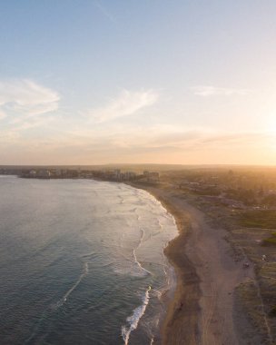 Sahildeki bitkilerin ve binaların ters hava görüntüsü günbatımı arka planında