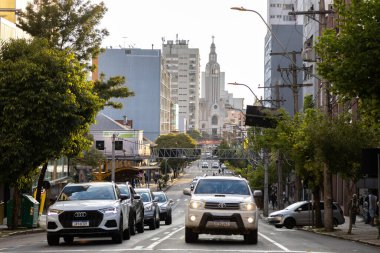 Caxias do Sul, Rio Grande do Sul, Brezilya - 5 Nisan 2022: Sinumbu Caddesi 'ndeki trafik ışıklarında bekleyen arabalar. Arka planda Sao Pelegrino
