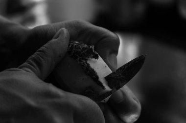 Patatesleri siyah ve beyaz arka planda soyarken çekilmiş yakın plan bir fotoğraf.