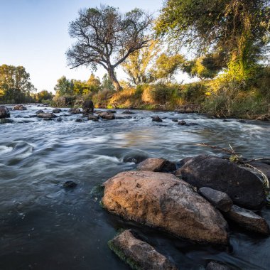 Güneşli bir günde taşların arasından akan bir nehir.