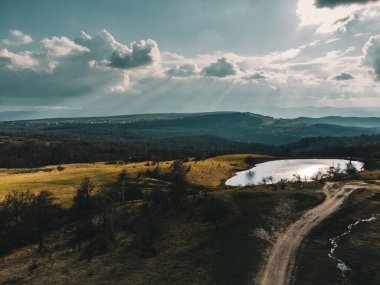 Yol kenarındaki yeşillik alanının hava görüntüsü ve Romanya 'daki sık ormanın arka planında küçük bir göl