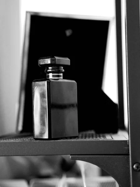 Eine Graustufen Nahaufnahme Einer Schwarzen Parfümflasche Auf Einem Metallgitterregal Mit — Stockfoto