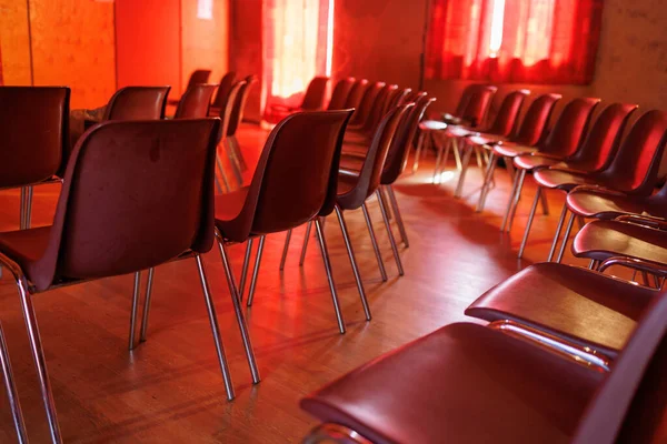 A closeup of Many chairs in a room for an event with red ambiance