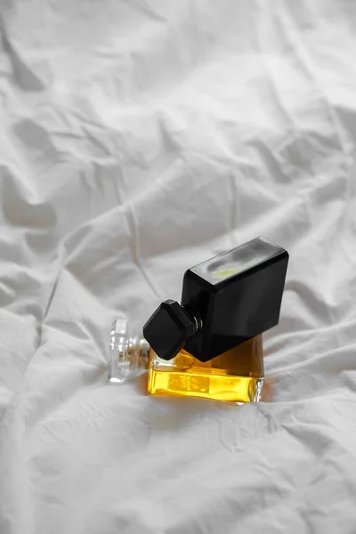一个垂直拍摄的两个香水瓶子在白色床单上模糊的背景 — 图库照片