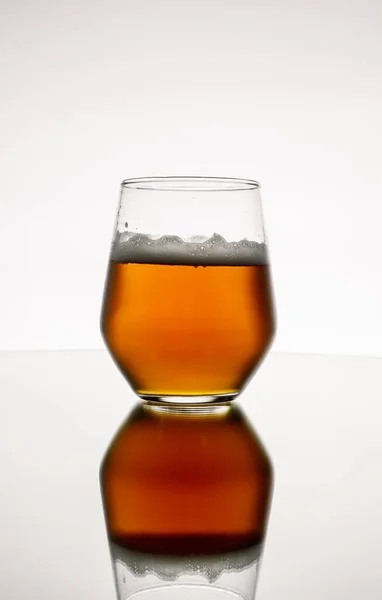 白い背景に白い背景に泡立つウイスキーのガラスの垂直閉鎖 — ストック写真