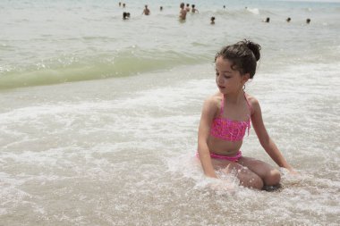Pembe bikinili kız güneşli bir yaz gününde kumsalda dalgalarla mutlu mesut oynuyor, Vera, İspanya