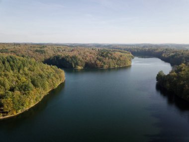 Güneşli bir günde, Almanya 'nın Neyetalsperre Gölü' nün yeşil sık ormanın ortasında mavi gökyüzüne karşı kuş bakışı bir bakış açısı.
