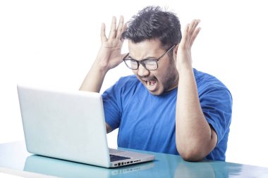 Genç adam bağırıyor, çığlık atıyor, dizüstü bilgisayarın önünde bağırıyor.