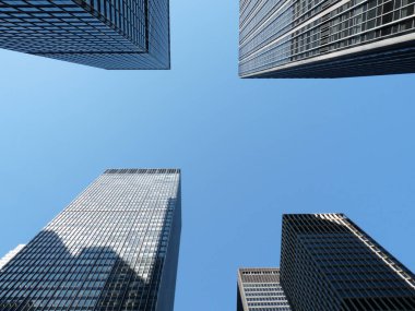 Mavi gökyüzü arka planında New York 'un yüksek binalarının alçak açılı görüntüsü.