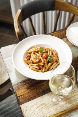 Beyaz tabakta karides ve soslu makarna. Şarap kadehli.