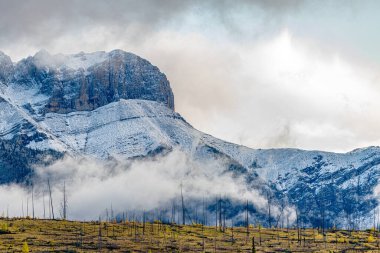 Bulutlu gökyüzüne karşı kayalık dağ zirvesi. Kanada doğası.