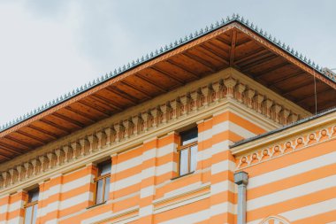 Pencereleri ve turuncu beyaz duvarları olan eski bir bina.