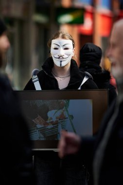 Büyük Britanya sokaklarında isimsiz bir maske takan kadın bir eylemci.