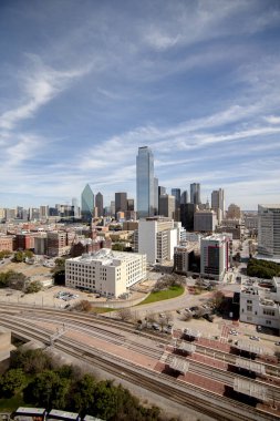 Dallas şehir merkezindeki bulutlu bir günde modern gökdelenlerle çekilmiş dikey bir fotoğraf.