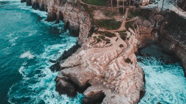 Mavi denizin kıyısındaki bir uçurumun kuş bakışı görüntüsü.