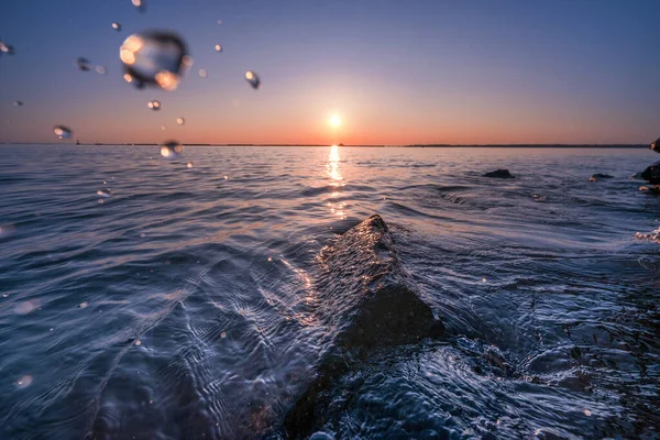 カメラの上に落ちる夕日の光線で海の波のクローズアップショット — ストック写真