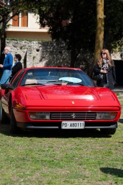 Kırmızı Ferrari 'nin dikey görüntüsü bir araba fuarında sergileniyor.