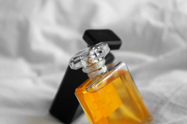 Bulanık arka planda beyaz bir çarşaf üzerinde iki parfüm şişesinin yakın plan çekimi.