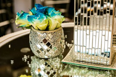 Bir restoranda ayna masasında süslenmiş güzel cam bir çiçek vazosu.