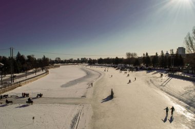 Gündüz karla kaplı alanda yürüyen insanların yüksek açılı görüntüsü.