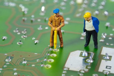 Elektronik devre kartı üzerinde çalışan teknisyenlerden oluşan bir ekibin yakın çekimi.