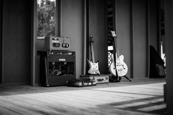 A grayscale shot of guitars and amp gear on a stage