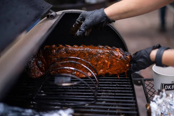 A chef\'s hands placing a piece of meat on a grill