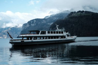 Dağlara karşı sudaki bir turist teknesinin görüntüsü.